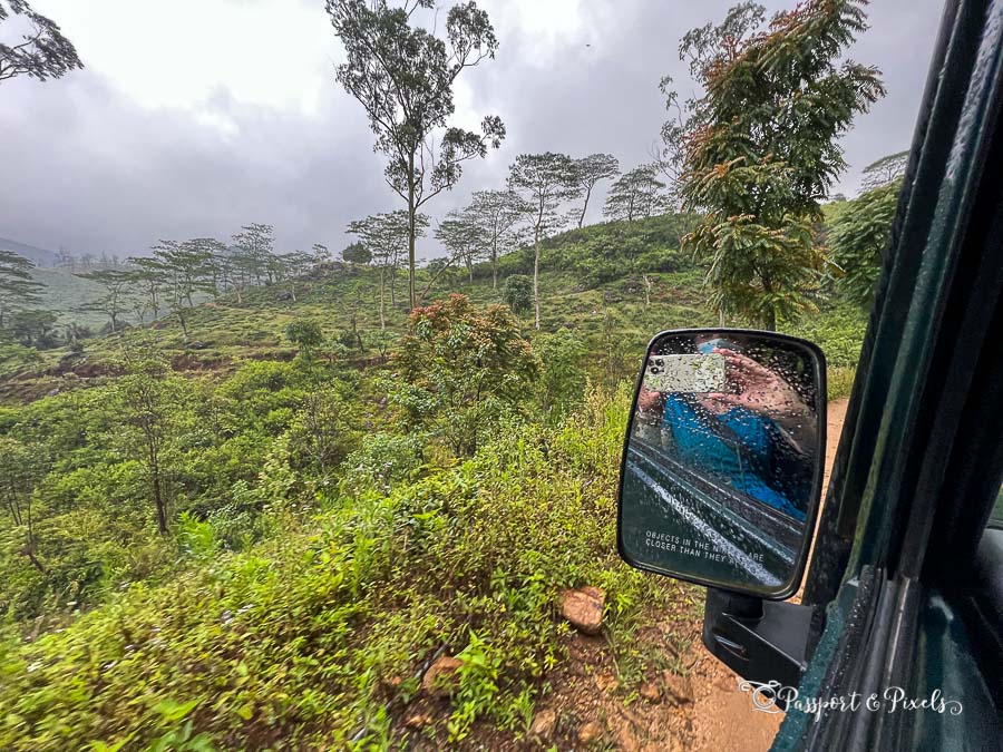 Photo taken from the window of the car of the Knuckles mountains and forest with rain clouds and rain drops on the wing mirror